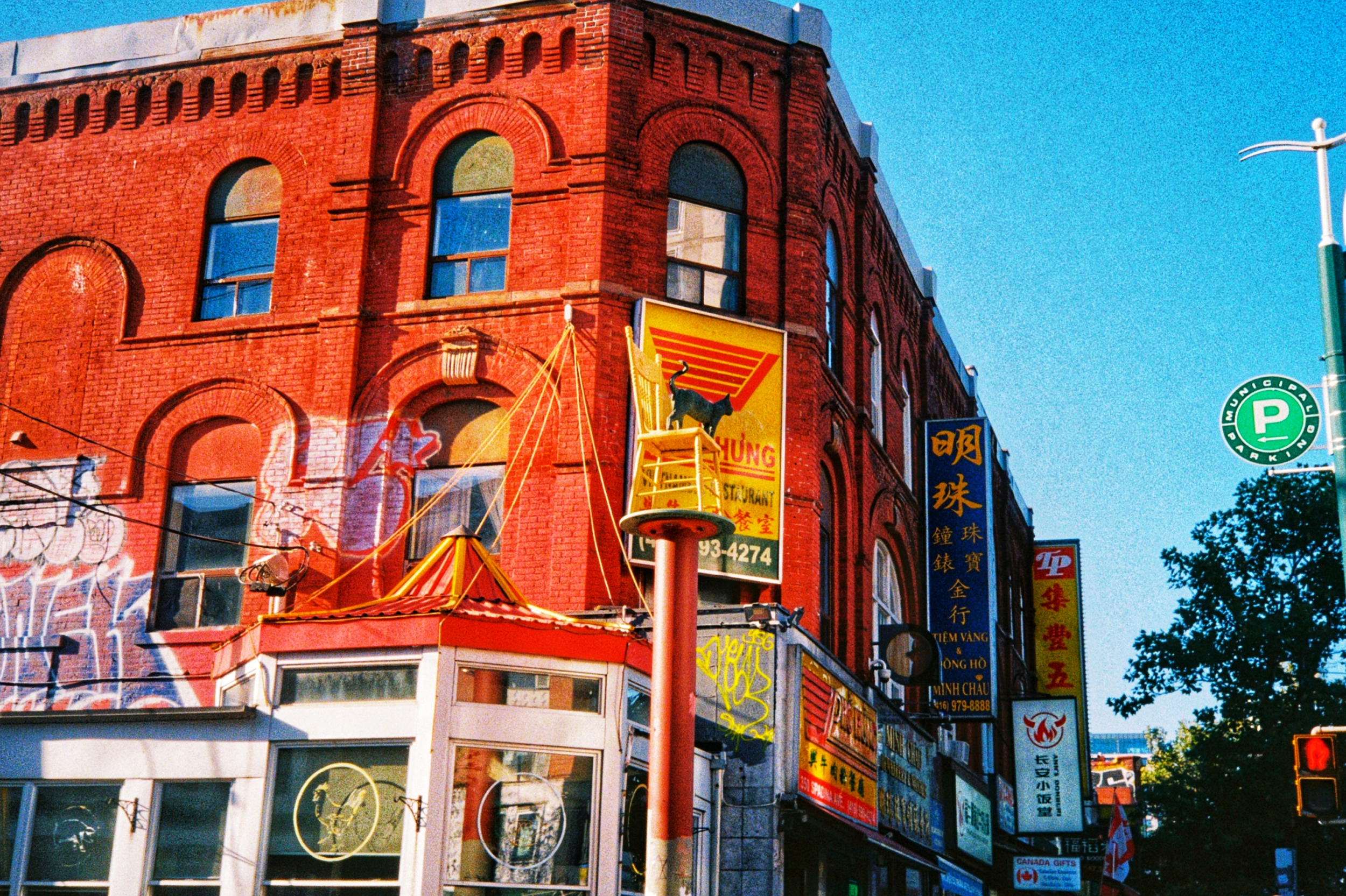 a brightly colored picture of a statue of a cat on a chair near a vietnamese restaurant