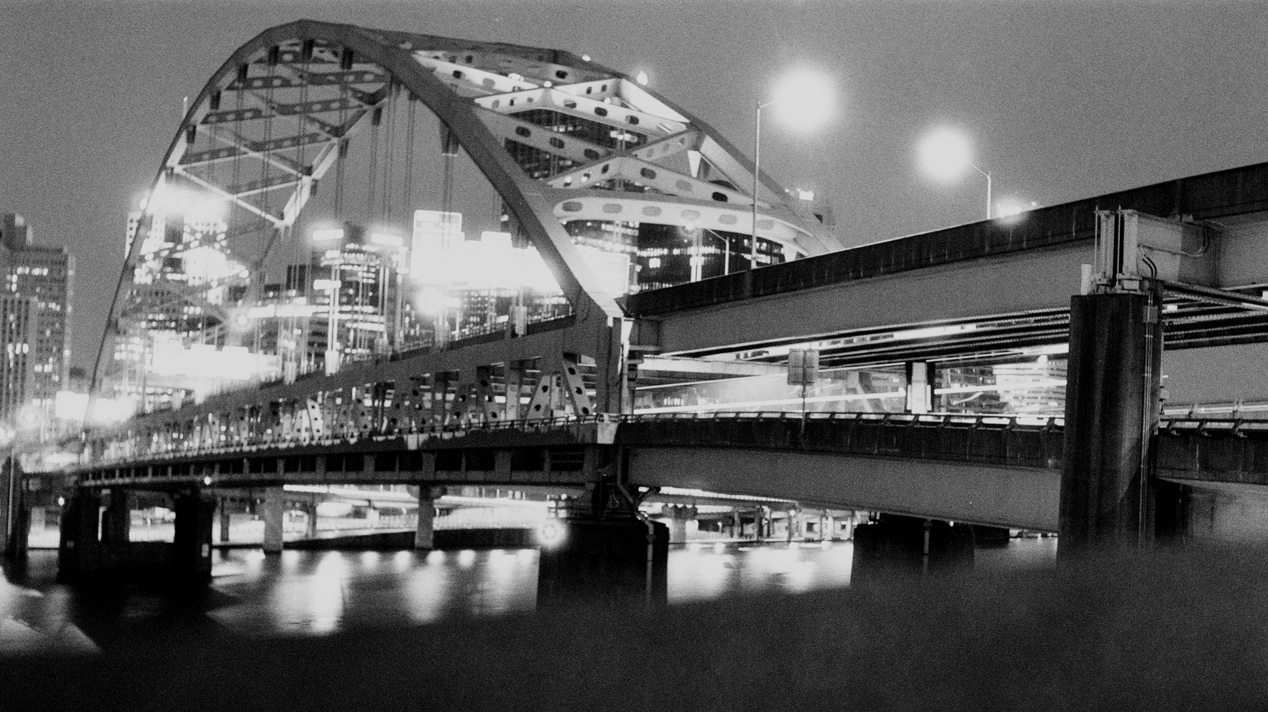 a black and white photo of a misty steel bridge from a slightly low angle
